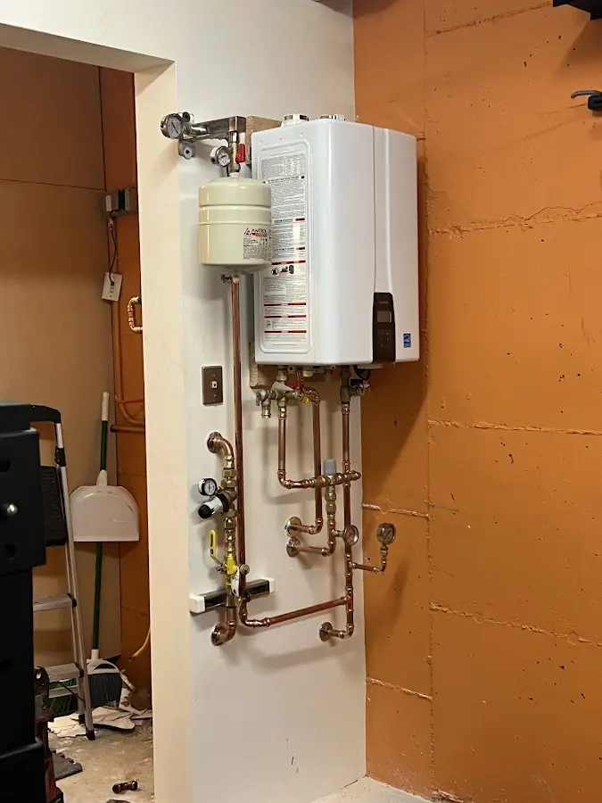 Plumbing technician inspecting water heater connections in Scio